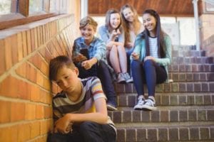 School Friends Bullying A Sad Boy In School Corridor